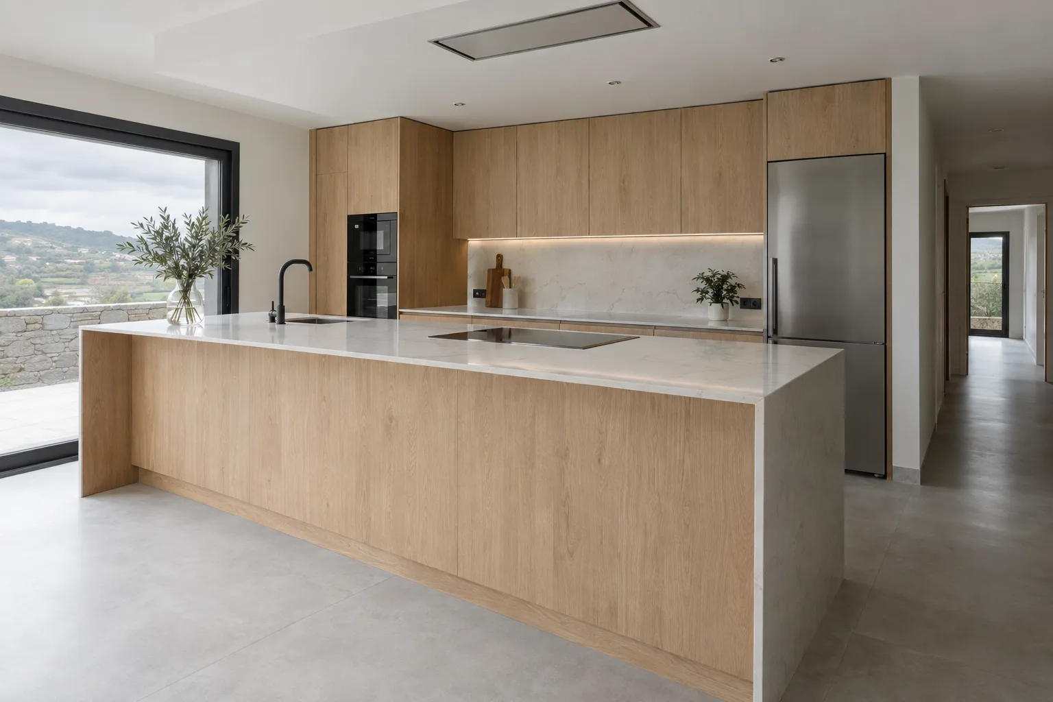 Cocina con peninsula en madera clara y encimera continua
