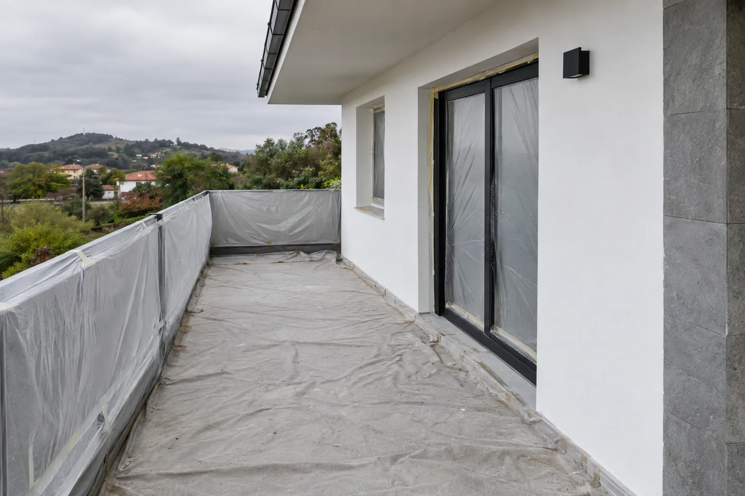 Terraza exterior con el paramento recién pintado y el suelo protegido