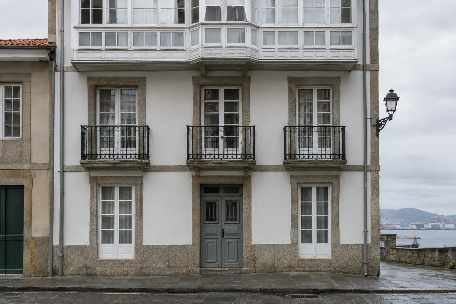 Fachada antigua de Ferrol con carpintería de madera y zócalo de granito
